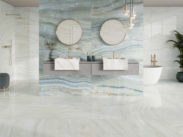 Lujoso cuarto de baño moderno con un suelo de marmol blanco brillante y una pared de acento de mármol veteado en tonos azules y verdes, con un tocador doble, lavabos sobre encimera y espejos redondos.