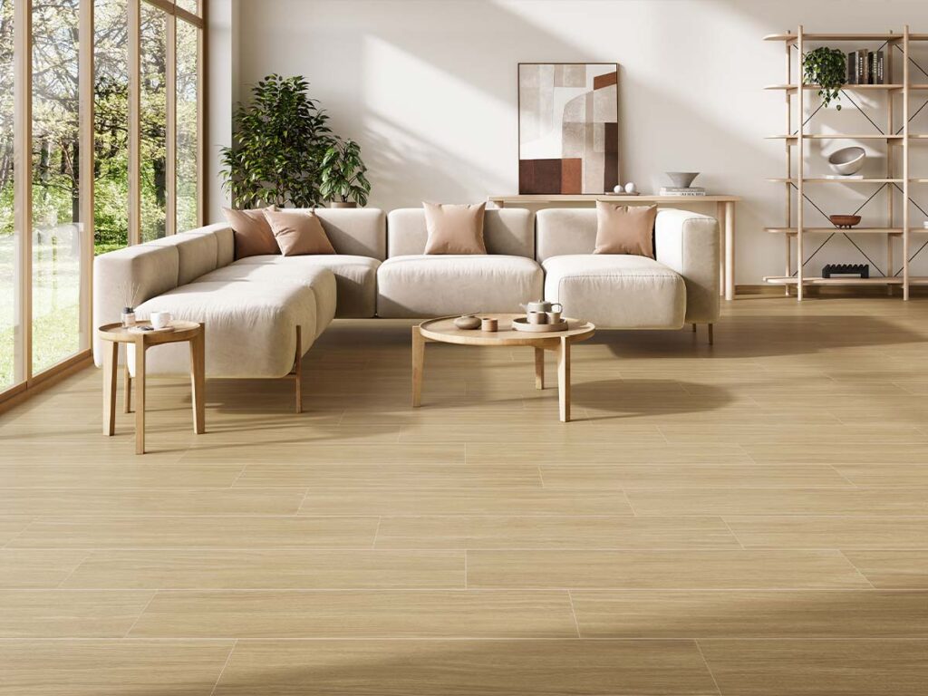 Pavimento porcelánico efecto madera clara en salón estilo nórdico con grandes ventanales y mobiliario en tonos neutros.