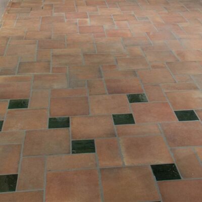 Suelo rústico interior de baldosas de barro cocido combinadas con tacos de cerámica en color verde.