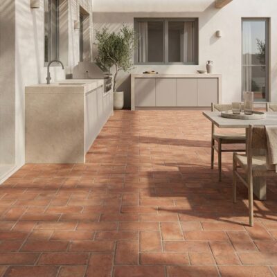 Un espacio de exterior con estilo mediterráneo, suelo de ladrillo de terracota, formato rectangular, tono rojizo, acabado mate.