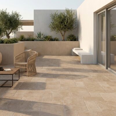 Terraza exterior con suelo porcelánico imitación piedra Sinai Taupe. Muebles de mimbre y olivos.