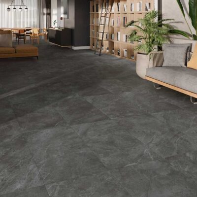 Amplia sala de estar y comedor de estilo moderno con un suelo de gres oscuro de efecto piedra y acabado mate.