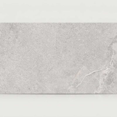 Un azulejo porcelánico rectangular de color gris claro con textura y vetas sutiles.