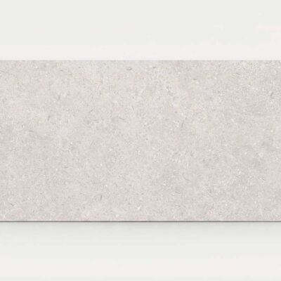 Azulejo porcelánico rectangular de efecto piedra Leiria Greige sobre fondo blanco.