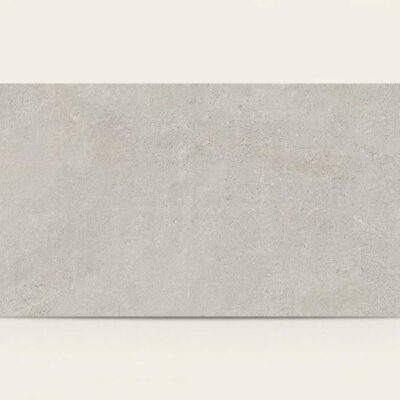 Baldosa porcelánica rectangular de imitación piedra en tono gris claro con textura rugosa.