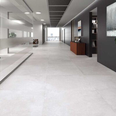 Pasillo de oficina moderno con suelos porcelanicos de gran formato. El acabado mate en tono gris claro aporta un estilo minimalista y elegante.