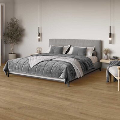 Dormitorio moderno con suelo porcelánico imitación madera Haspe Roble, cama gris y planta.