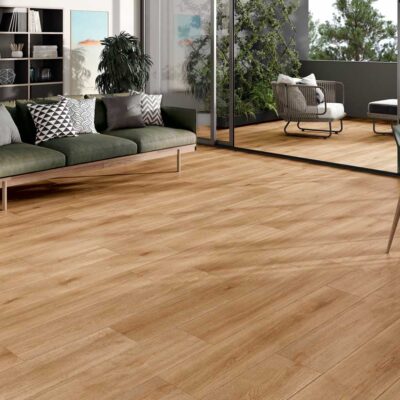 El suelo porcelánico imitación madera Nordby Honey luce en un salón con balcón.
