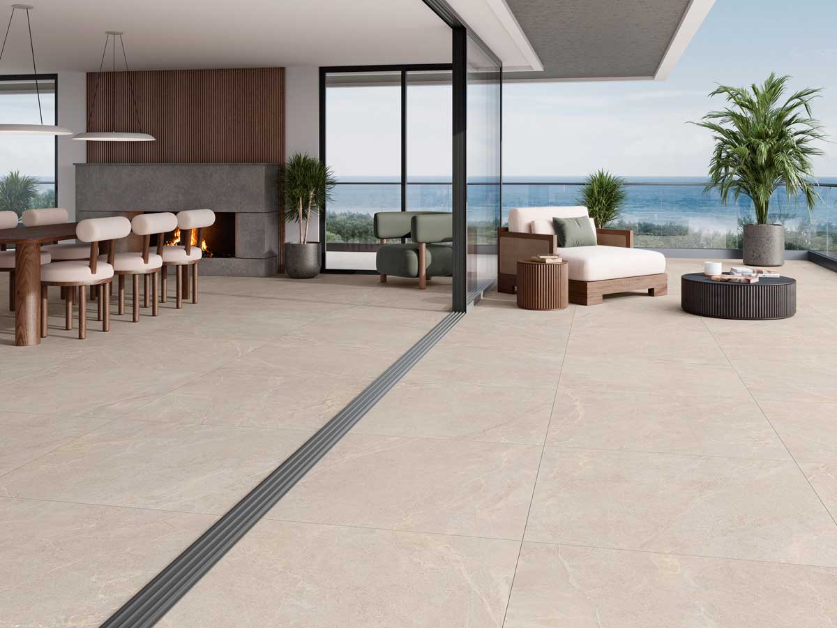 Salón abierto a terraza con suelo porcelánico beige continuo y vistas al mar.