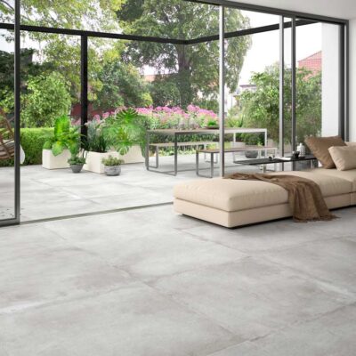 Suelo porcelánico imitación cemento gris claro en salón y patio exterior.