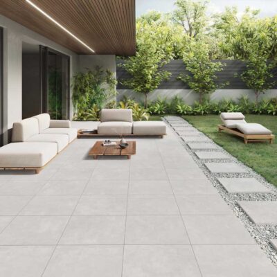 Patio exterior moderno con suelo porcelánico Columbia Pearl gris claro y mobiliario de jardín.