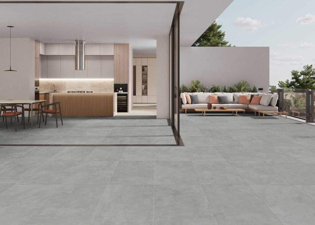 Suelo porcelánico efecto cemento gris oscuro en una cocina y terraza modernas.