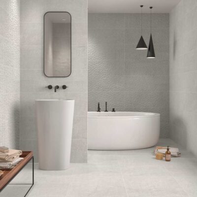 Suelo porcelánico Newbury Grey efecto piedra en un baño moderno con bañera y lavabo blanco.