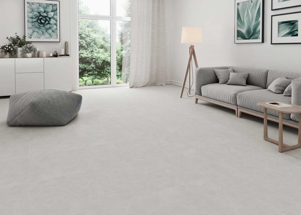 Un salón moderno con suelo porcelánico gris efecto cemento y grandes ventanales.