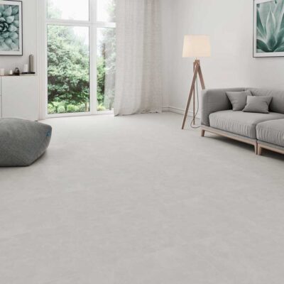 Un salón moderno con suelo porcelánico gris efecto cemento y grandes ventanales.