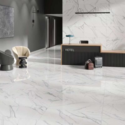 Lobby de hotel moderno con elegantes suelos porcelánicos blancos de efecto mármol y acabado pulido. Las baldosas grandes reflejan la luz.