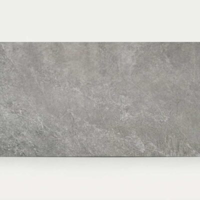 Azulejo rectangular de suelo porcelánico gris con efecto piedra sobre fondo blanco.