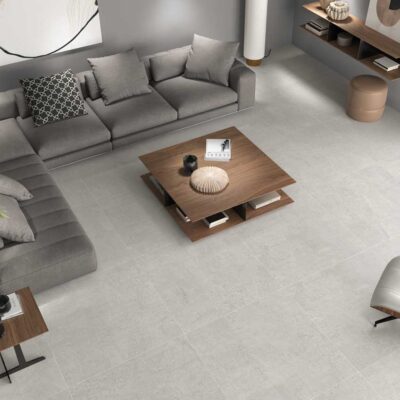 Salón moderno con suelo porcelánico gris claro imitación piedra. Sofá, mesa de centro y sillones.