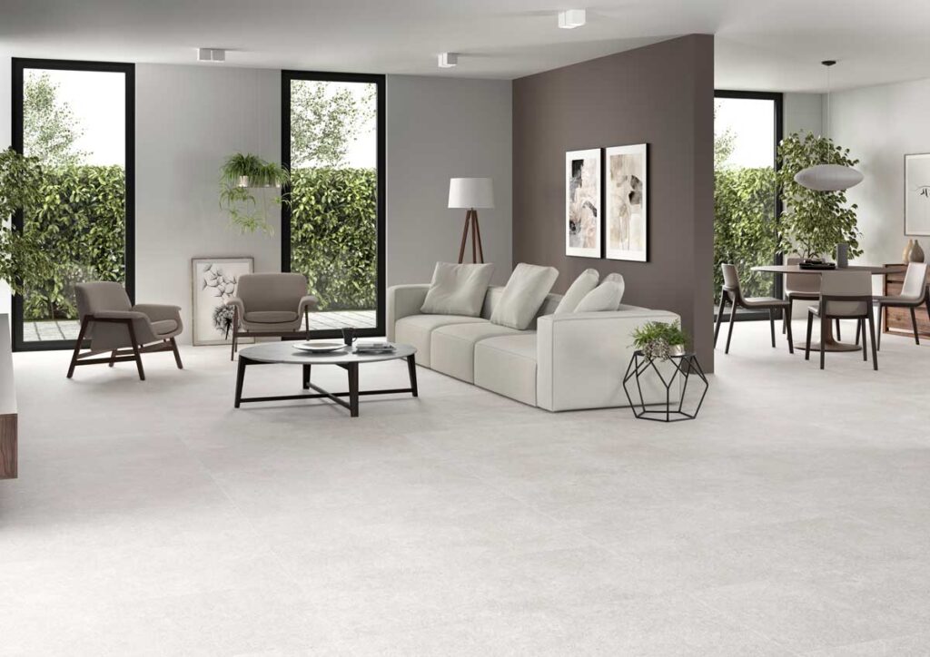 Amplio salón y comedor con suelo porcelanico efecto cemento greige y mobiliario moderno.