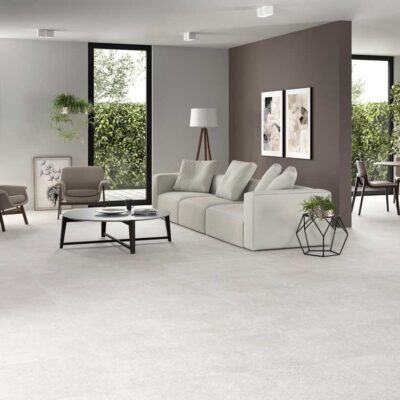 Amplio salón y comedor con suelo porcelanico efecto cemento greige y mobiliario moderno.
