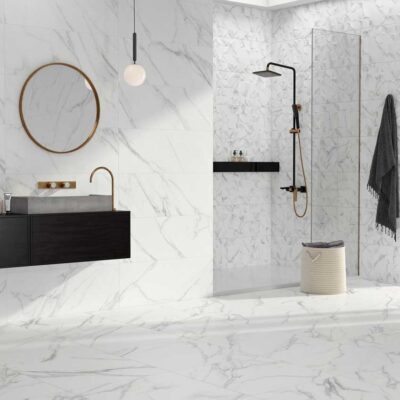 Baño moderno con suelo porcelánico blanco imitación mármol y paredes a juego. Mueble negro, espejo redondo y ducha negra.