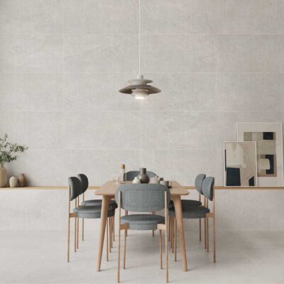 Moderno comedor con suelo porcelánico gris imitación piedra y pared a juego. Mesa de madera y sillas grises.
