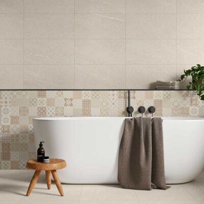 Baño con azulejo porcelánico imitación piedra Halton Cream en paredes y suelo, con bañera blanca.