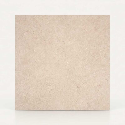 Un azulejo porcelánico beige con textura de piedra se muestra sobre un fondo blanco.