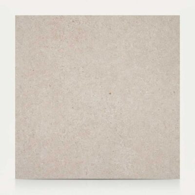 Azulejo porcelánico cuadrado beige claro con textura de piedra y sutiles tonos rosados.