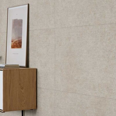 Pared revestida con azulejo porcelánico imitación piedra Lomma Bone en un salón moderno.