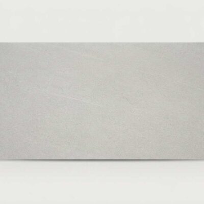 Baldosa porcelánica gris efecto cemento Halton Grey con textura sutil sobre fondo blanco.