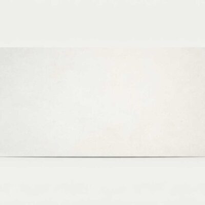Baldosa porcelánica rectangular blanca con textura de cemento sobre fondo neutro.