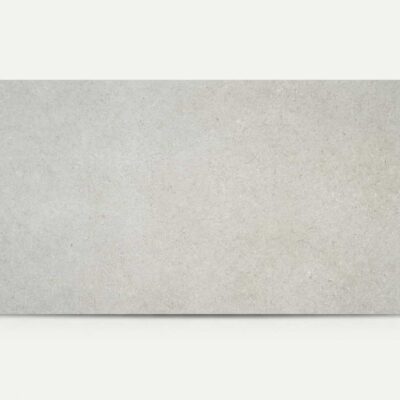 Baldosa porcelánica rectangular Lomma Grey gris claro con sutil textura de piedra.