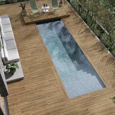 Suelo porcelánico imitación madera Concorde Natural rodea una piscina moderna con zona de relax.