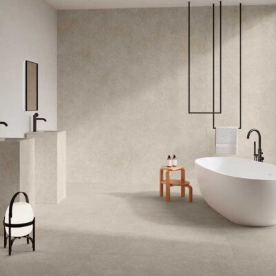 Suelo porcelánico antideslizante Lomma Bone en un baño moderno con bañera y lavabos.