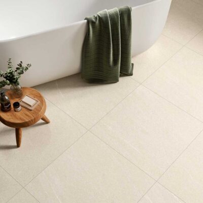 Suelo de baño porcelánico beige Halton Cream en un baño moderno con bañera y taburete.