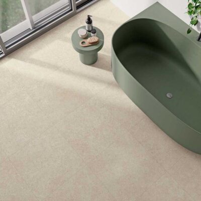 Suelo porcelánico beige efecto piedra en un baño moderno con bañera verde.