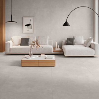 Suelo porcelánico imitación cemento gris en un salón moderno con sofás claros.