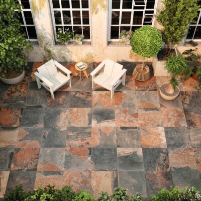 Patio exterior con suelo porcelánico Castleford Natural. Las baldosas son de tonos grises y rojizos.