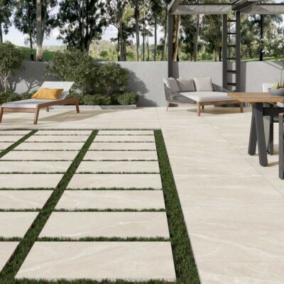 Patio exterior con suelo porcelánico beige imitación mármol. Se aprecian tumbonas y un comedor.