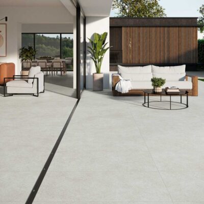 Amplio salón y patio exterior con suelo porcelánico gris imitación piedra. Diseño
