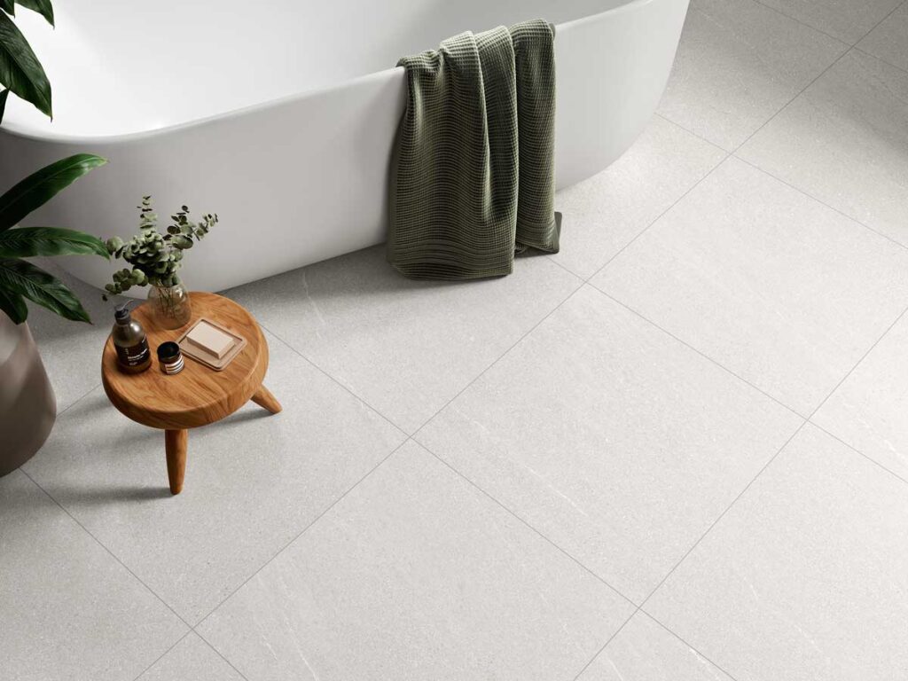 Suelo porcelánico Halton White imita piedra en un baño moderno con bañera y taburete.