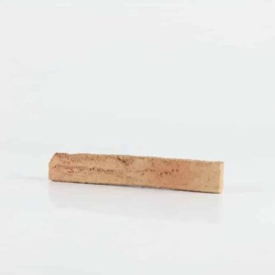 Pieza rectangular de ladrillo cerámico visto con superficie rugosa y acabado destonificado en tonos beige cálidos, ideal para revestimiento de pared interior.