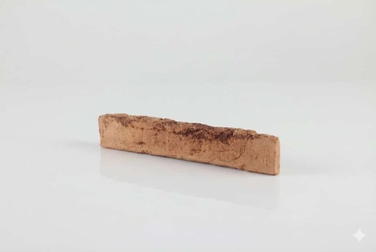 Pieza rectangular de barro cocido con superficie texturizada en tonos cálidos salmón y marrón. Acabado rústico y mate characteristic de la baldosa de terracota enarenada.