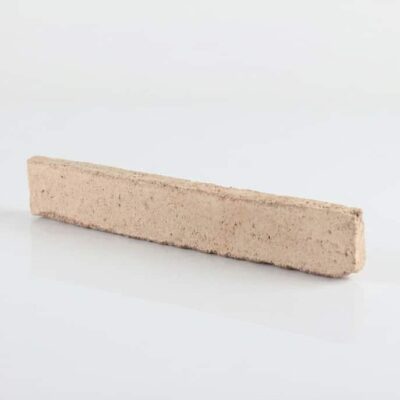 Pieza rectangular de baldosa cerámica con acabado rústico en tono blanco crema, superficie texturizada con aspecto de piedra natural y cantos irregulares.
