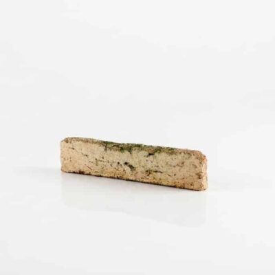 Pieza rectangular de baldosa cerámica con acabado enarenado en tonos beige y musgo, textura rugosa y superficie mate que imita piedra natural.