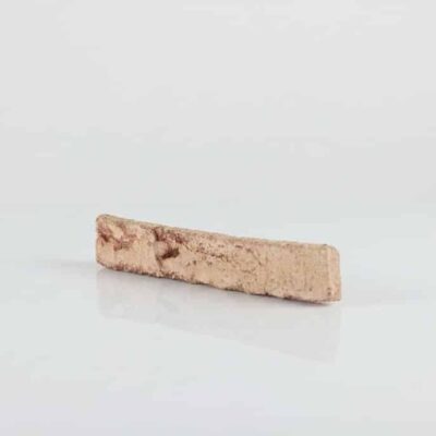 Pieza rectangular de baldosa cerámica con acabado enarenado en tonalidad salmón, superficie rugosa y texturizada con puntos oscuros dispersos, apta para revestimiento de pared.