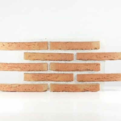Piezas rectangulares de baldosa de barro cocido con tonalidades cálidas variables, dispuestas en hiladas alternas con malla de refuerzo visible entre ellas. Acabado rústico con textura irregular característica del barro cocido tradicional.