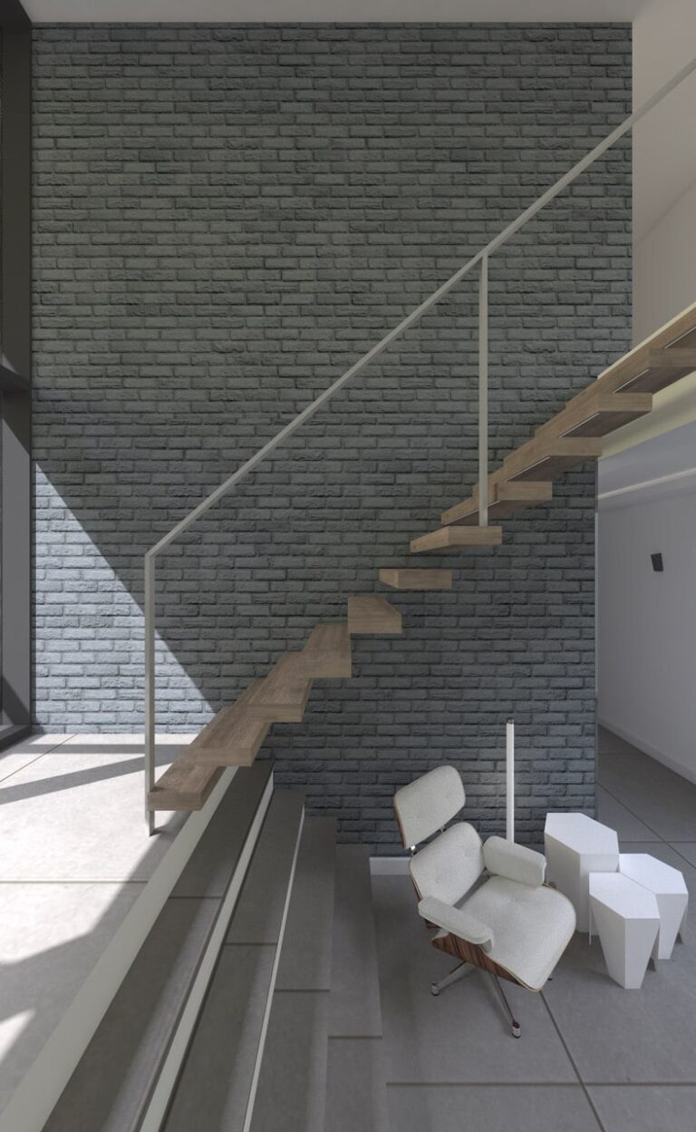 Interiores modernos con escalera flotante de madera y pared revestida en gres porcelánico de imitación ladrillo gris. Barandilla metálica blanca y mobiliario minimalista complementan el espacio luminoso.