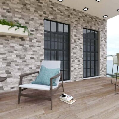 Terraza contemporánea con suelo porcelánico imitación madera en tonos grises y mobiliario de diseño. Pared de aplacado de hormigón efecto ladrillo gris, grandes ventanales negros y detalles verdes con plantas decorativas.